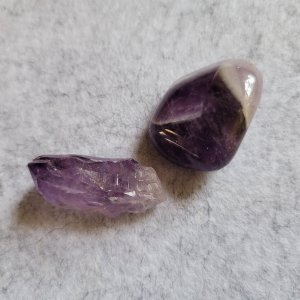 An amethyst crystal, raw, and tumbled amethyst. Deep purple and white